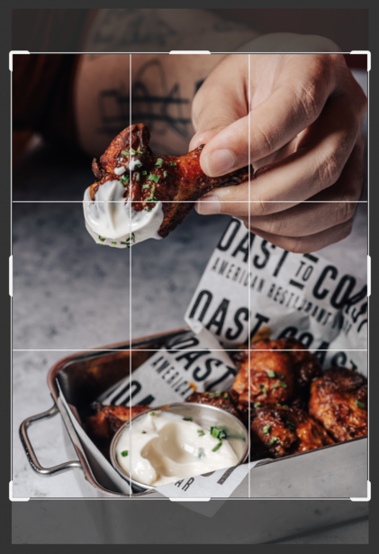 Hand placing a spoonful of whipped cream onto a dessert plate with baked goods and sauce.