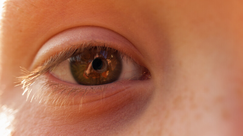 Close-up of a child's eye with warm amber-brown iris and golden reflections.