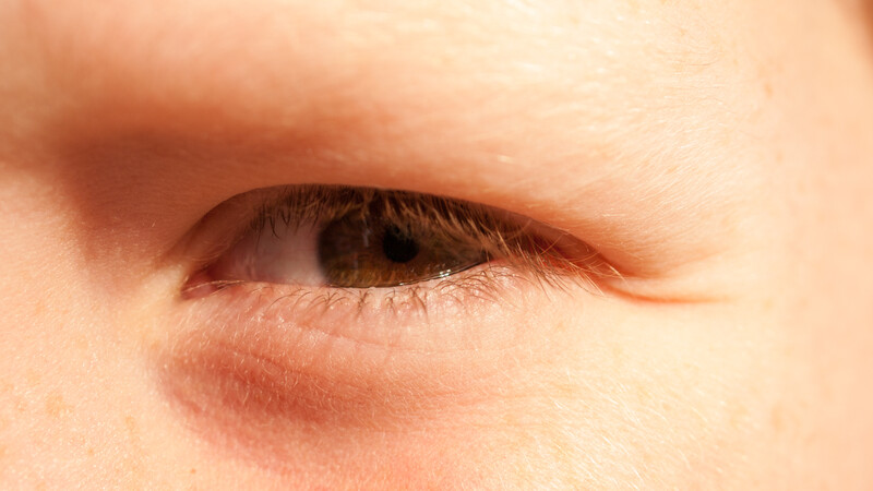 Close-up of a person's eye with brown iris and visible eyelid and lashes.