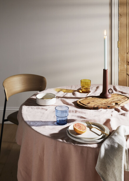 Minimalist table setting with two place settings, brass chair, and soft natural window light.