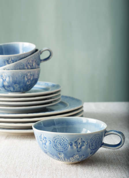 Stack of blue and white ceramic dishes with decorative patterns and matching bowls with handles.