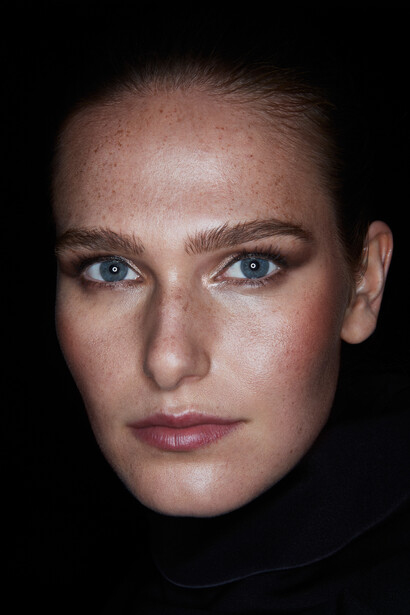 Close-up portrait of a woman with blue eyes against a black background.