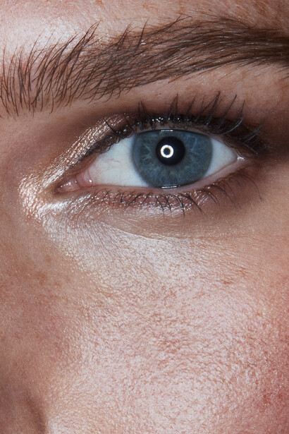 Close-up of a blue human eye with detailed iris texture and natural eyelashes.