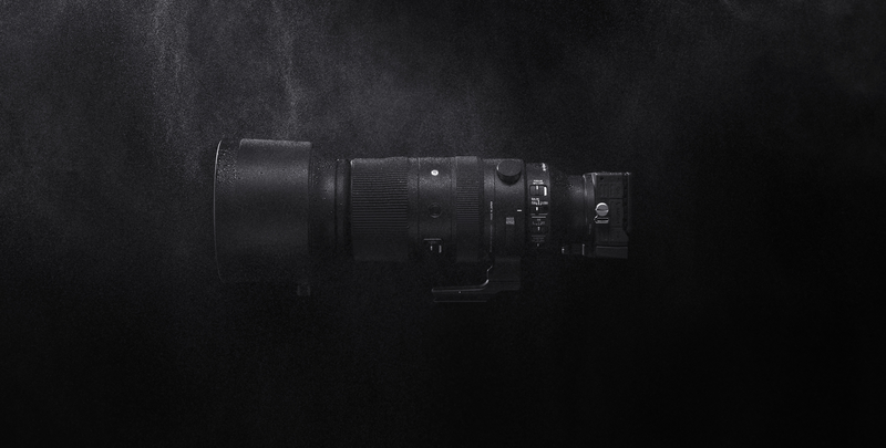 Telephoto lens mounted on a camera body, photographed against a dark textured background.