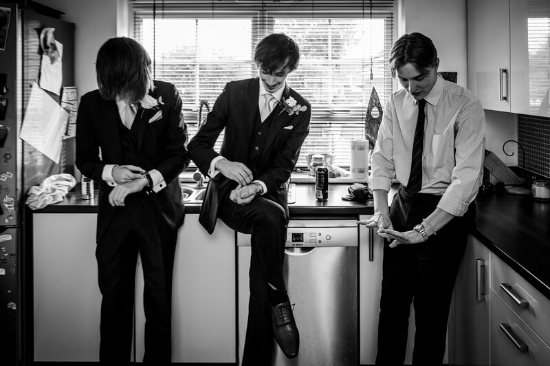 Three people in business attire standing in an office kitchen, examining documents together.