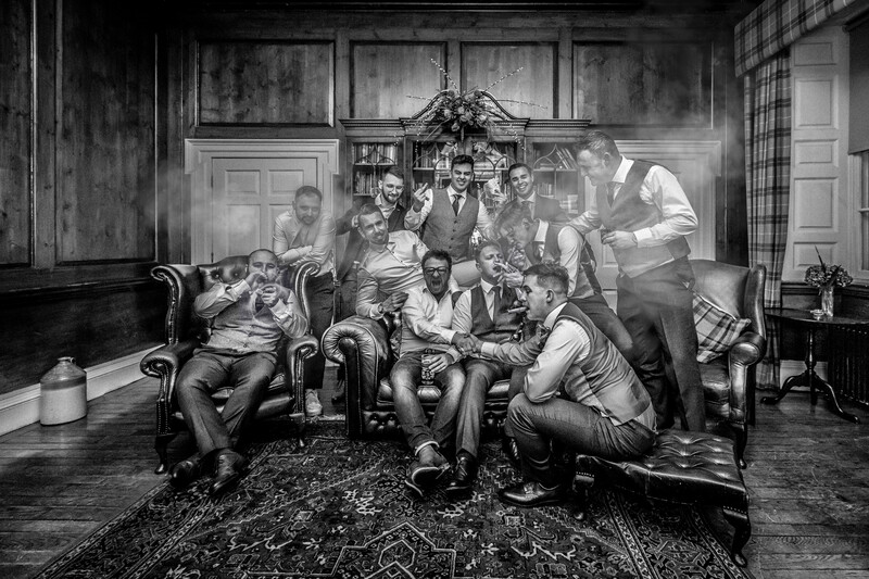 Large group of men in vintage clothing gathered in an ornate interior room, rendered in black and white.