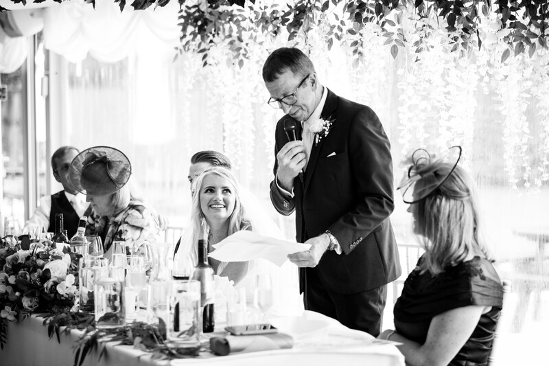 Man giving a toast at a formal dinner while seated guests listen attentively.