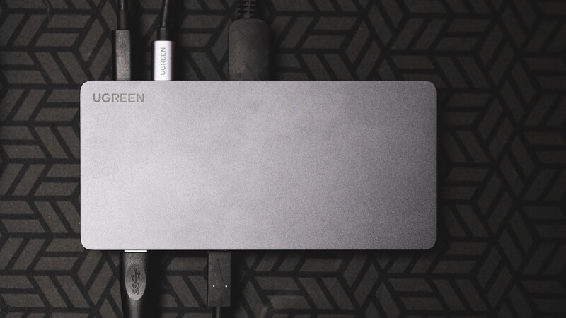 Ugreen laptop cooling pad with cables arranged on a geometric patterned surface.