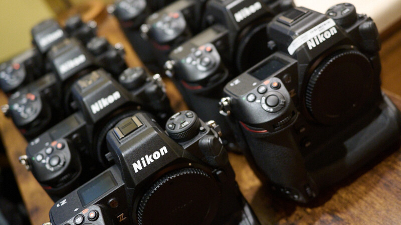 Multiple Nikon DSLR camera bodies arranged on a wooden surface.