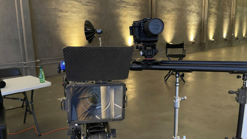 Professional film lighting setup with softbox, camera on crane, and monitoring equipment in studio.