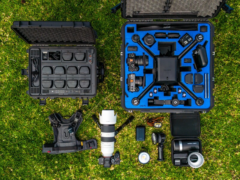 Overhead view of camera equipment and protective cases arranged on green grass.