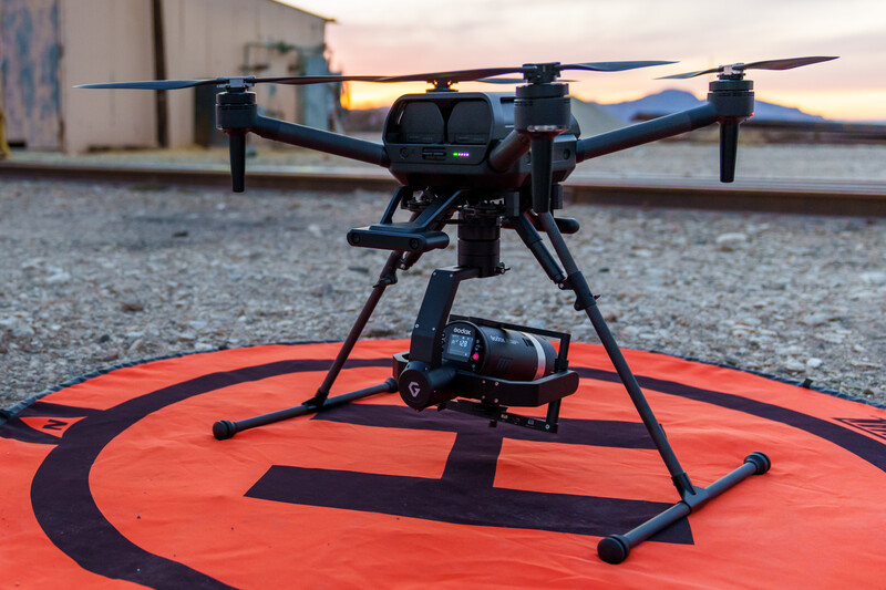 Professional drone with camera gimbal mounted on a red and black landing pad during golden hour.