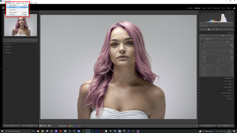 Woman with long pink wavy hair wearing a white strapless top against a neutral gray background.