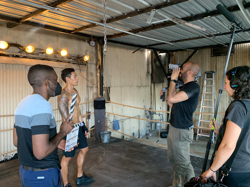Photography workshop in an industrial studio space with instructor demonstrating camera technique to a group of students.