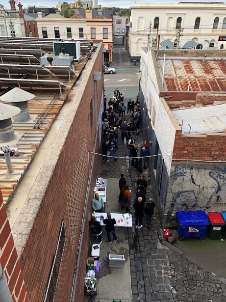 Overhead view of a narrow alley with a crowd of people gathered between brick and stone buildings.