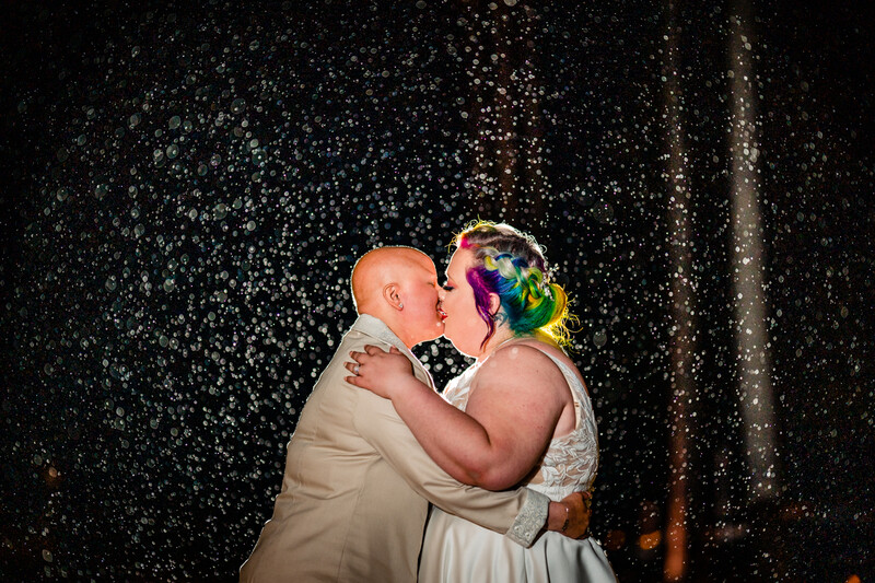Couple kissing under falling confetti at night with dark background and warm lighting.