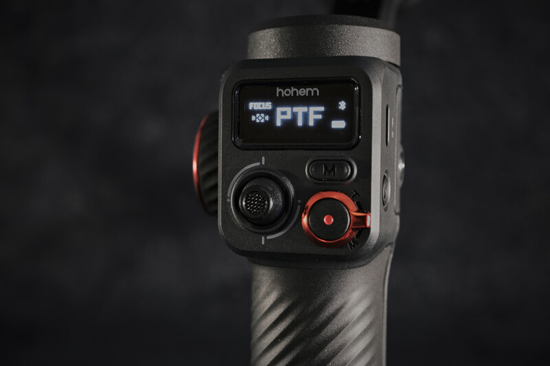 Handheld thermal imaging camera with digital display and control buttons mounted on tripod.