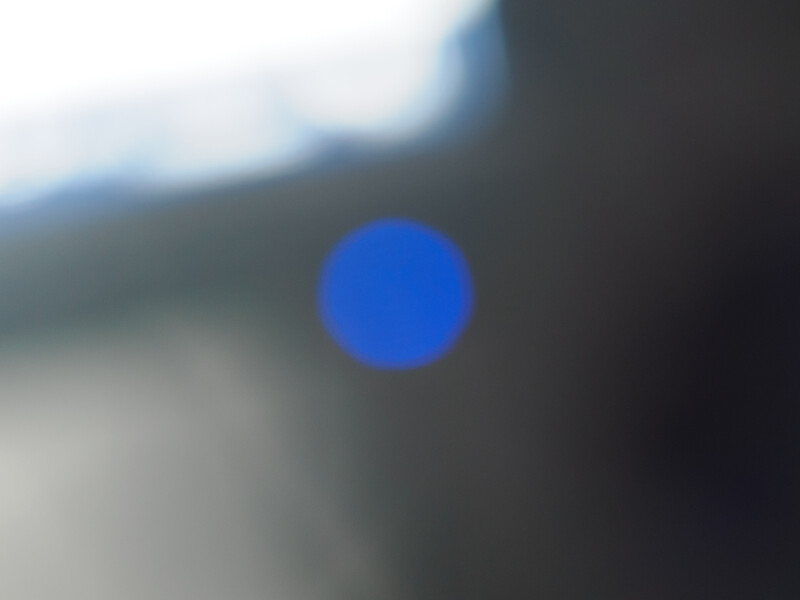 Bright blue circle centered on a blurred, dark background with subtle blue tones.