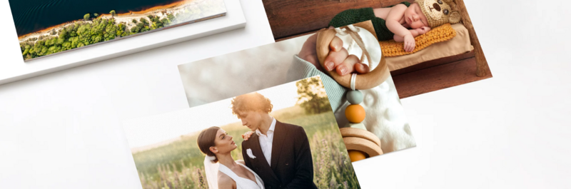 Printed photo samples and canvas prints arranged on white surface showing various portrait and landscape photography styles.