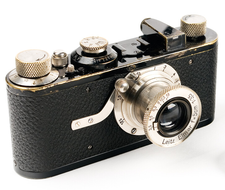 Vintage black rangefinder camera with brass accents and chrome lens assembly.