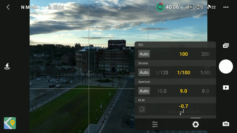 Screenshot of manual camera settings interface showing ISO 100, shutter speed 1/100, and aperture f/9.0 during golden hour cityscape photography.
