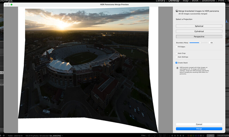 Aerial view of a large stadium at sunset with golden light illuminating the sky and surrounding landscape.