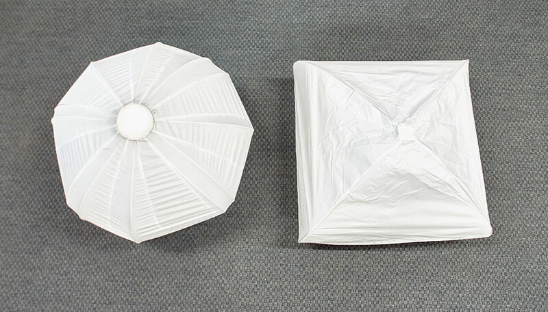Two white collapsible softbox diffusers displayed flat on gray fabric surface.