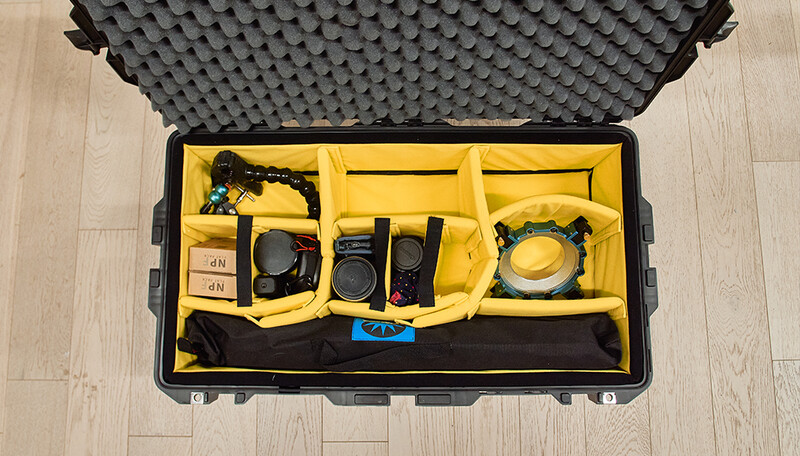 Professional camera gear organized in a foam-lined hard case with yellow padded dividers.