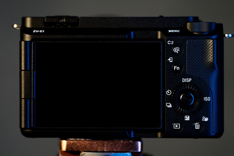 Rear view of a compact digital camera with LCD screen and control buttons visible.