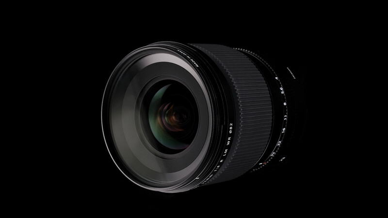 Wide-angle camera lens with internal glass elements visible through front optics, photographed against black background.