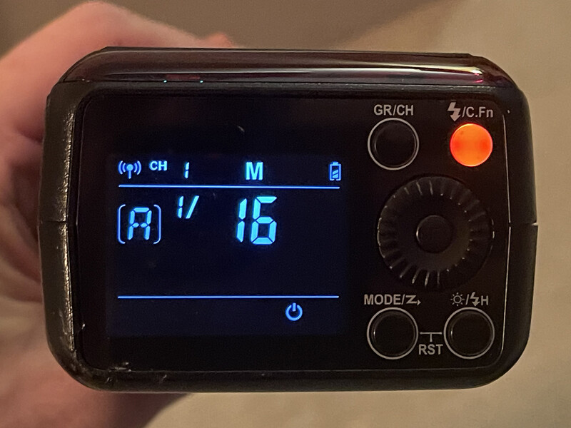 Close-up of a handheld light meter displaying blue LCD readout with channel, mode, and exposure value information.