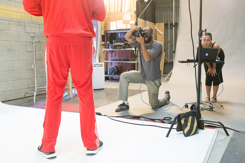 Studio setup with photographer taking portrait of person in red outfit, using professional lighting and equipment.