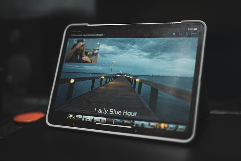 Screenshot of photo editing software displaying a pier at dusk with blue-hour lighting and color grading adjustments visible in the timeline.