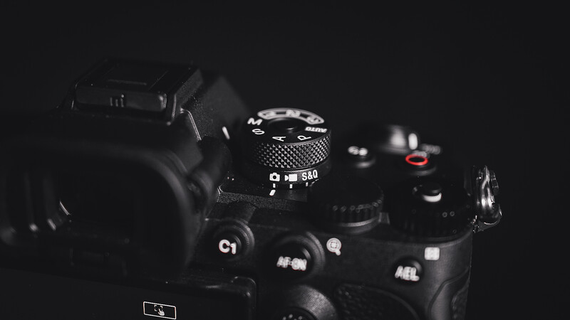 Professional DSLR camera body with lens and accessories arranged on dark surface.