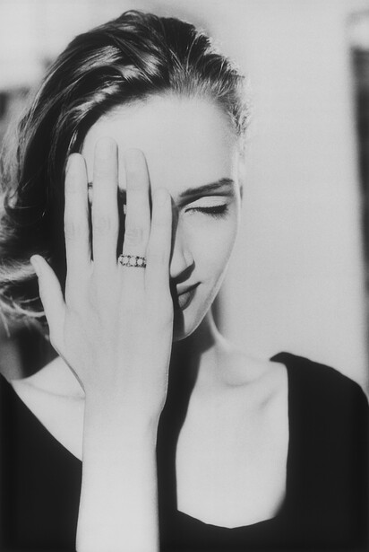 Black and white portrait of a woman with hand partially covering her face and eyes closed.