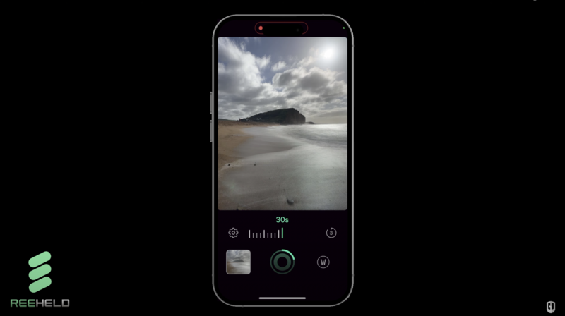 Screenshot of a smartphone camera app displaying a beach landscape with overcast sky and rocky headland during a 30-second exposure.