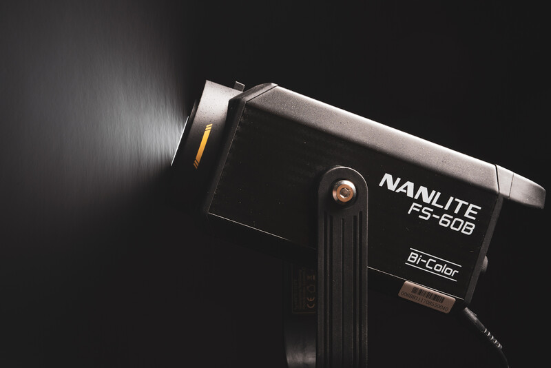 Nanlite FS-60B LED light fixture mounted on a stand, emitting a bright beam against a dark background.