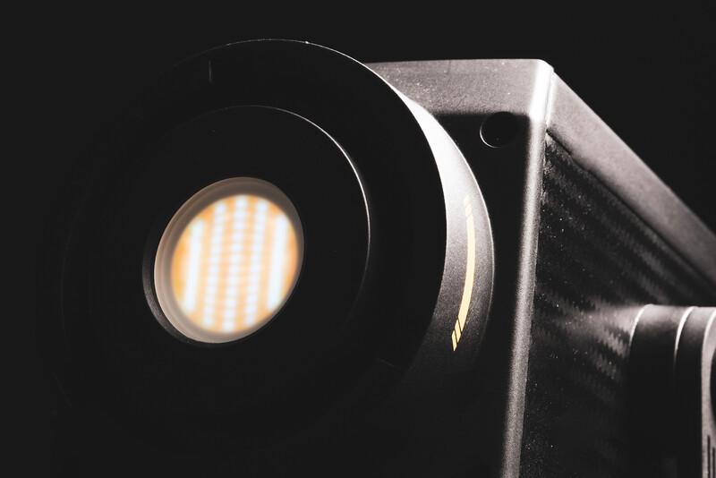 Close-up of a professional LED panel light with illuminated vertical bars creating warm, even output against dark background.