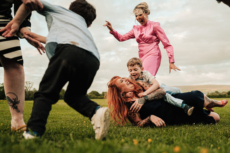 Multiple people playing tag on a grass field under overcast sky.