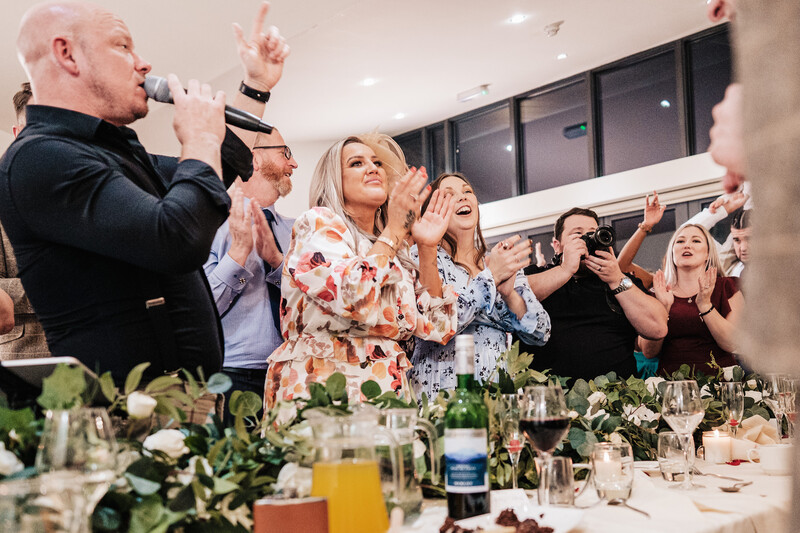 Man speaking into microphone at formal event while woman and guests applaud.