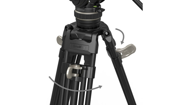 Close-up of a video camera tripod head with fluid pan and tilt controls and adjustable leg spreaders.
