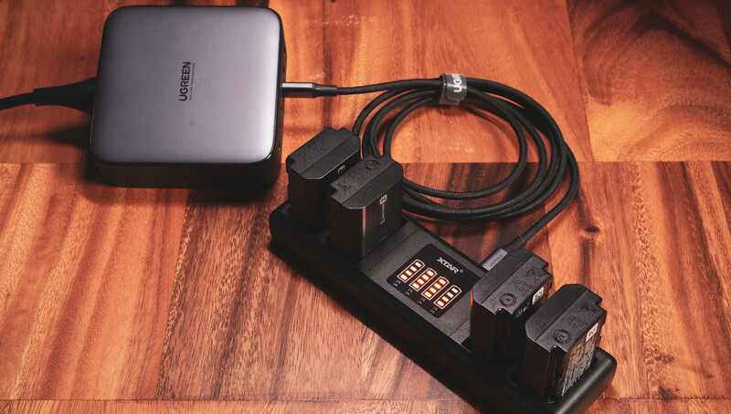 Photography lighting kit with power supply, wireless trigger receiver, and two flash units on wooden surface.