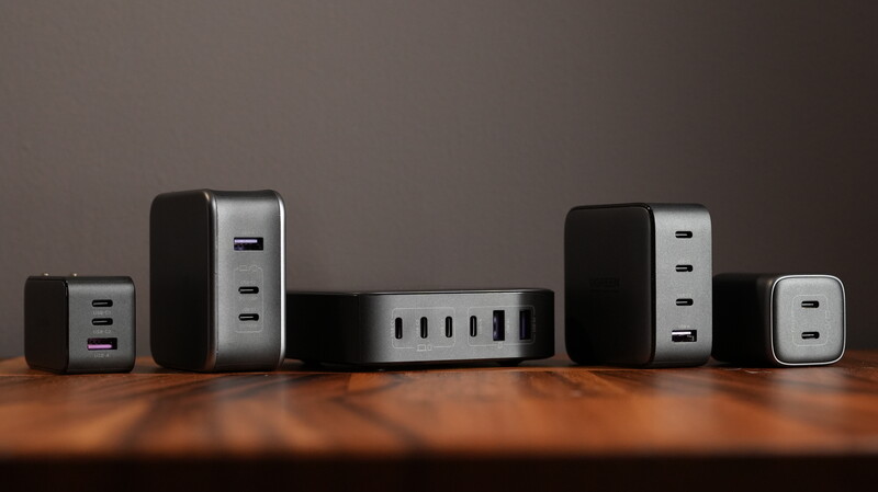 Collection of USB power adapters and charging hubs arranged on a wooden surface against a neutral background.