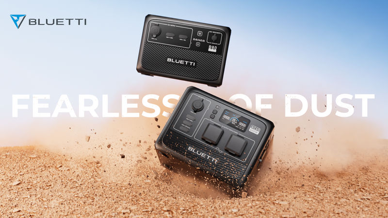 Two portable power station units positioned in blowing desert sand against a clear blue sky.