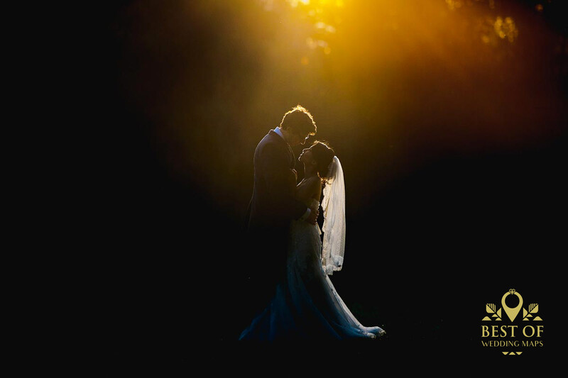 Bride and groom silhouetted against warm golden backlighting during their first dance.