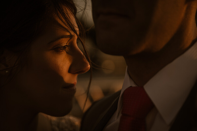 Woman in profile with warm golden side lighting, intimate moment with another person partially visible.