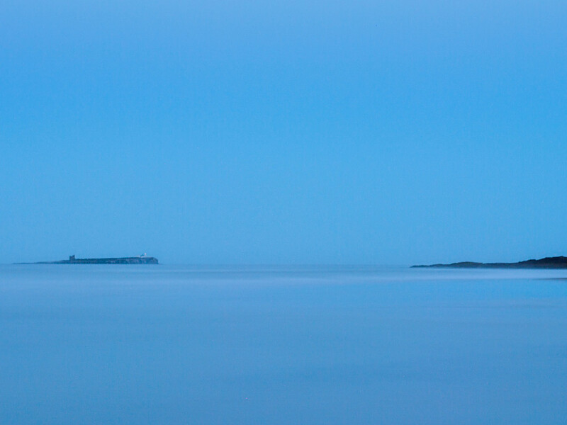 Minimalist seascape with a distant ship on calm blue water under clear sky.
