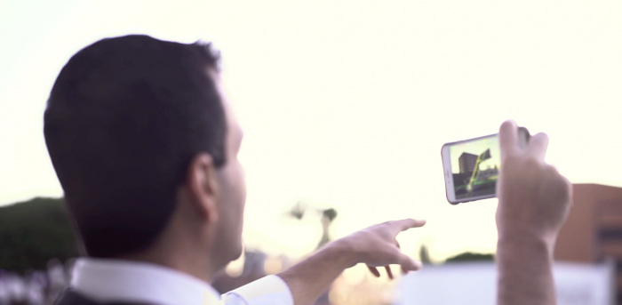Person holding a smartphone to photograph the sky at golden hour, pointing at the screen while composing a shot.