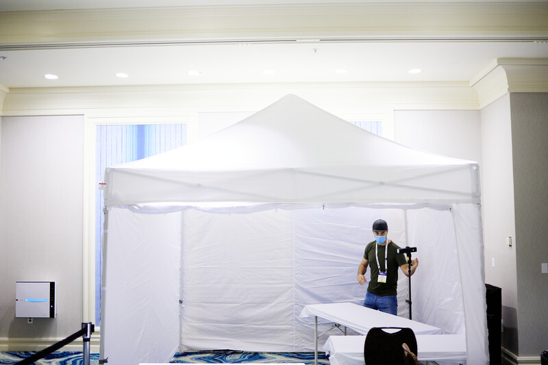Photographer shooting inside a white pop-up tent studio setup in an indoor space.