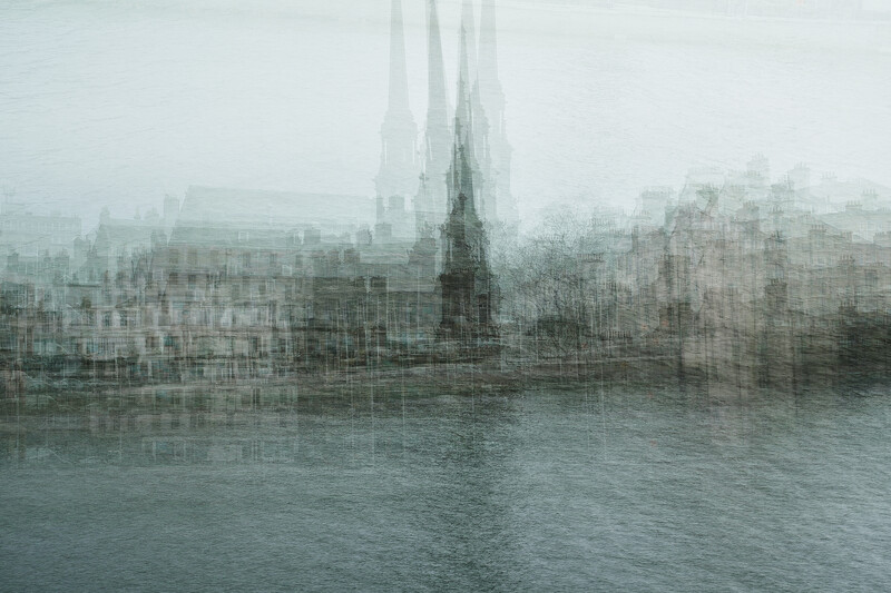 Gothic cathedral spire rising through heavy mist above a densely built waterfront cityscape.
